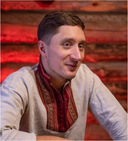 Парень в русской народной рубашке на фоне бревенчатой стены